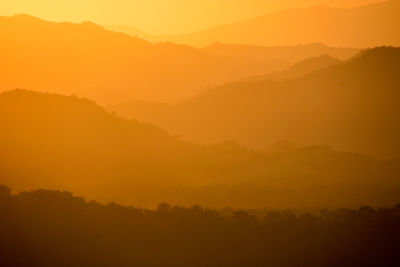 Scenic view of silhouette mountains against orange sky