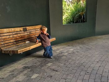 Boy standing by bench