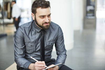 Businessman writing notes in diary while sitting at office