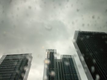 Low angle view of modern buildings against sky during rainy season