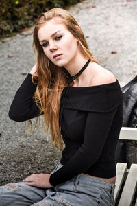 Beautiful young woman looking away while sitting on bench