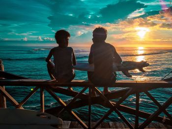 Silhouette people at beach against sky during sunset