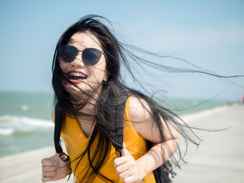 Portrait of woman wearing sunglasses against sea