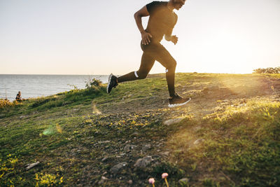 Young man running on hill near sea