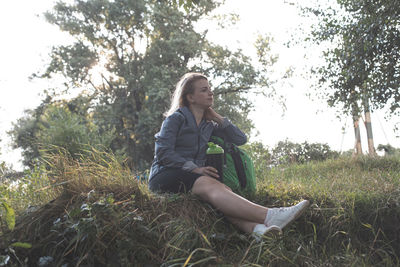 Low angle view of young woman sitting on grassy field