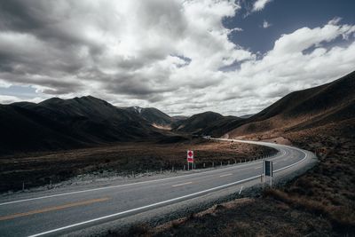 View of country road on mountain against cloudy sky