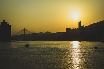 View of suspension bridge over river at sunset