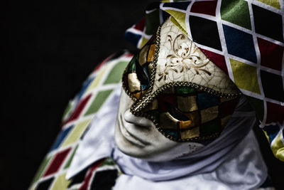 Close-up of man wearing mask against black background