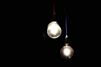 Close-up of illuminated light bulb against black background