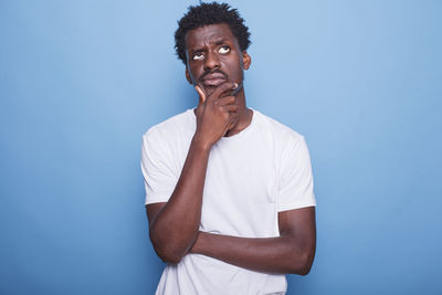 Portrait of young woman using mobile phone against blue background