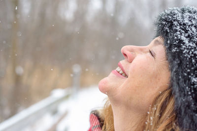 Close-up of smiling woman during snowfall