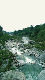 Rocks by river against clear sky