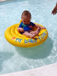 High angle view of boy sitting on inflatable ring in swimming pool