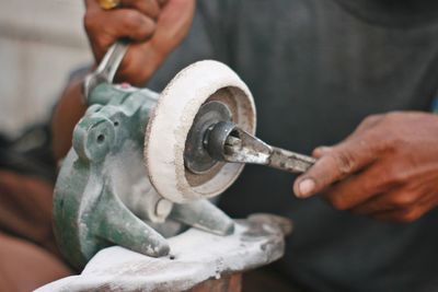 Low section of man repairing power tool in workshop