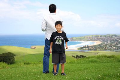 Full length of boy standing on sea shore against sky