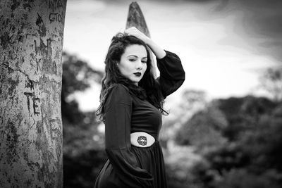 Portrait of woman standing against tree trunk