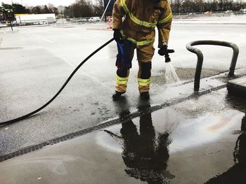 Low section of man standing on wet street