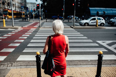 Rear view of man crossing road in city