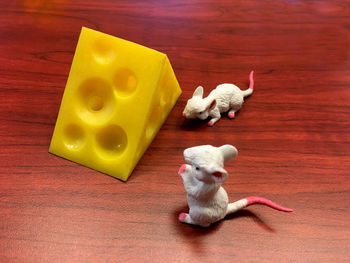 High angle view of toy mice with artificial cheese cube on table