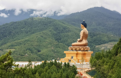 Statue by temple against mountain