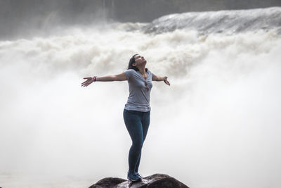 View of a woman on a rock with open arms, expressing freedom and