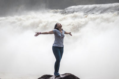 Full length of young woman standing against sky