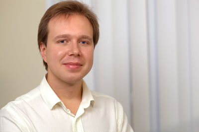 Portrait of confident young businessman sitting against blinds