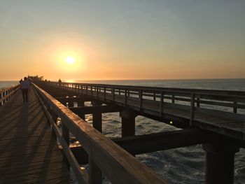 Pier over sea against clear sky during sunset