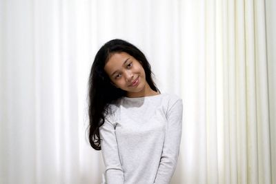 Portrait of a smiling young woman standing against curtain