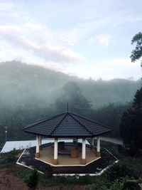 House amidst trees and buildings against sky