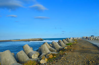 Rocks by sea against blue sky