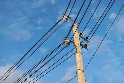 Low angle view of power lines against blue sky