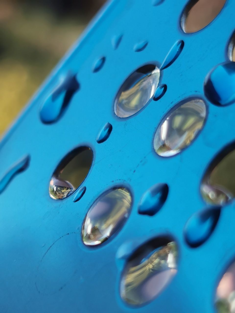 CLOSE-UP OF WATER DROPS ON BLUE METALLIC SURFACE