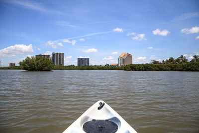 Buildings by river against sky