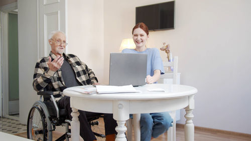 Side view of young woman using mobile phone while sitting at home