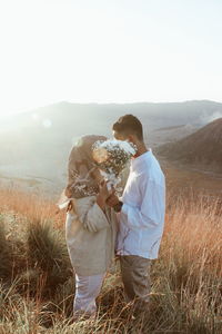 Rear view of couple on field against sky