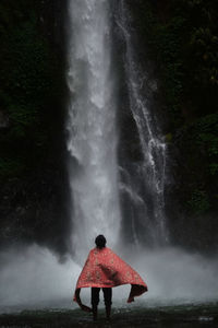 Rear view of man standing against waterfall