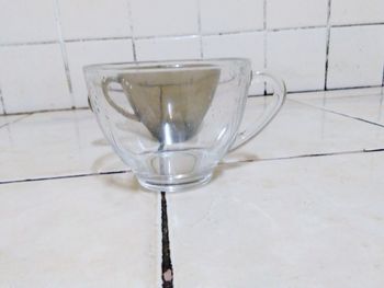 Close-up of wineglass on table against white wall