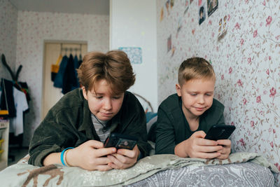 Children enjoy playing the game on the phone while lying on the bed.