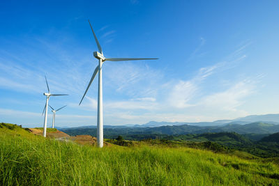 Scenic view of wind turbines on field against sky