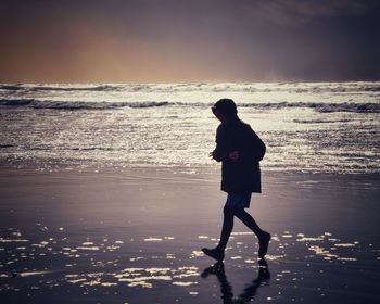 Full length side view of woman on beach against sky