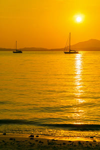 Sailboat sailing on sea against sky during sunset