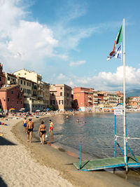 People at beach against sky in city