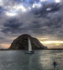 Boat sailing in sea against cloudy sky