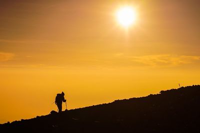 Silhouette hiker at mt fuji against orange sky during sunset