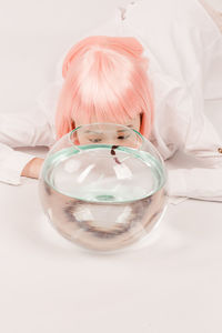 Close-up of woman by fish swimming in glass bowl on floor