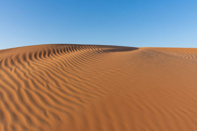 Sand dunes in desert against clear sky