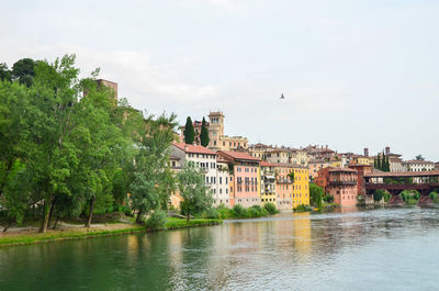 Buildings by river against sky in city