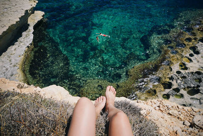 Low section of woman on rock in sea