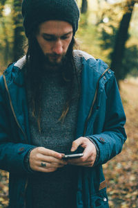 Man using smart phone while standing in forest